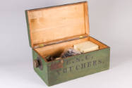 Green wooden storage box containing knobs and tuning dials